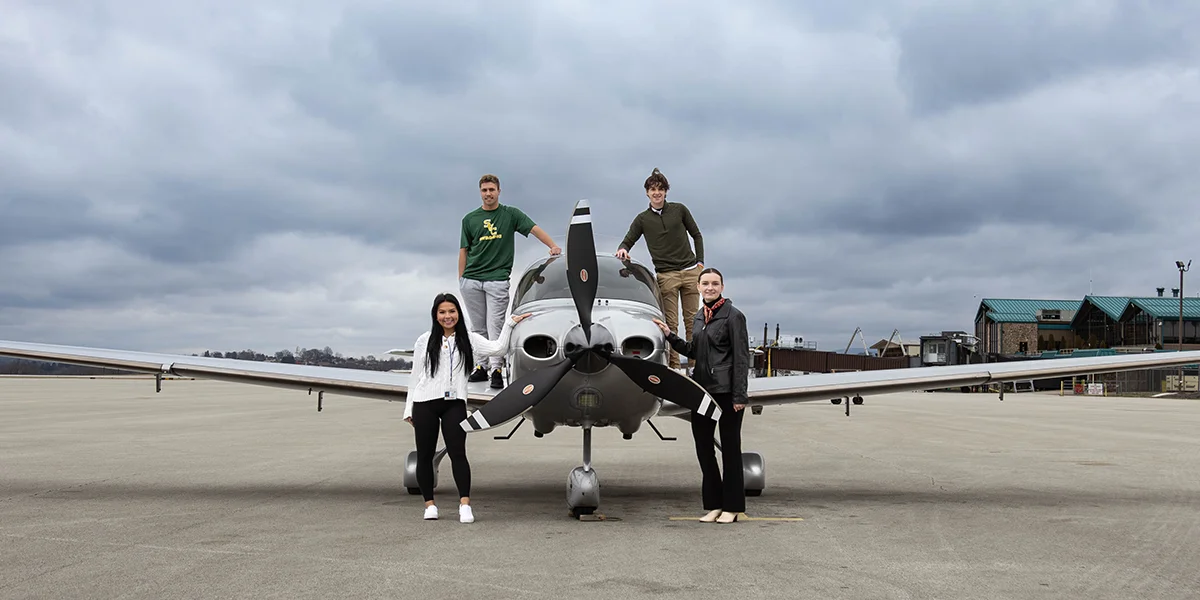 aviation management majors stand around small airplane