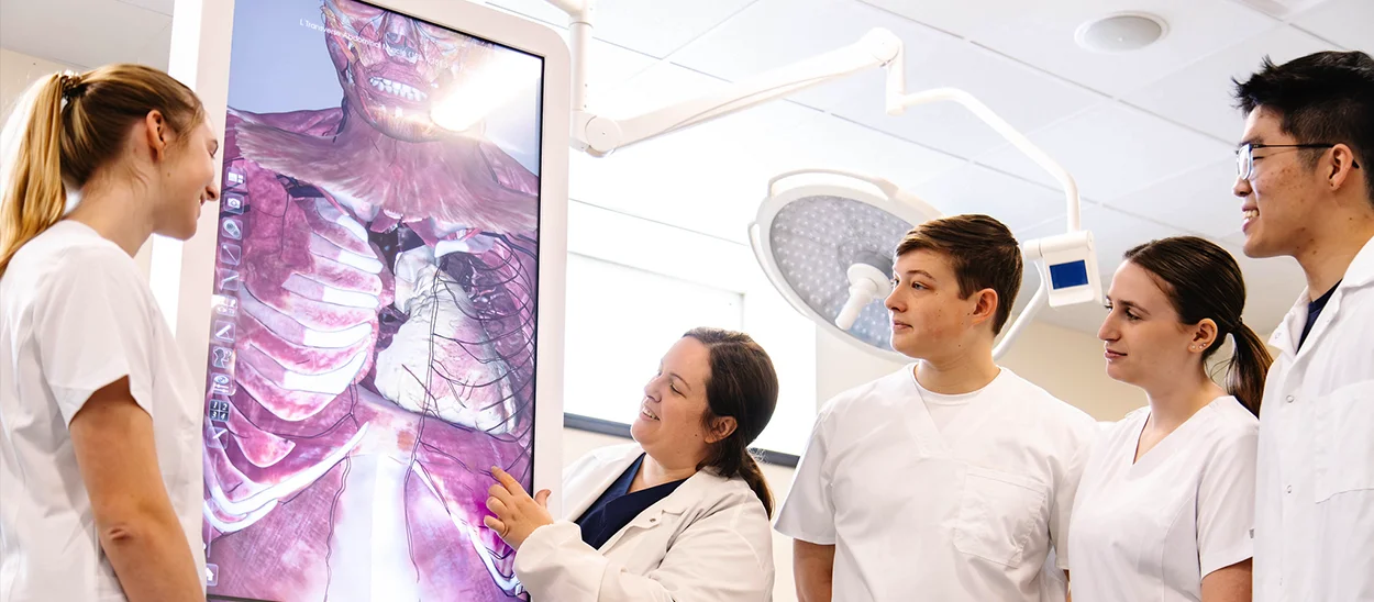 Medical students engaging with a digital anatomy display during a hands-on learning session.