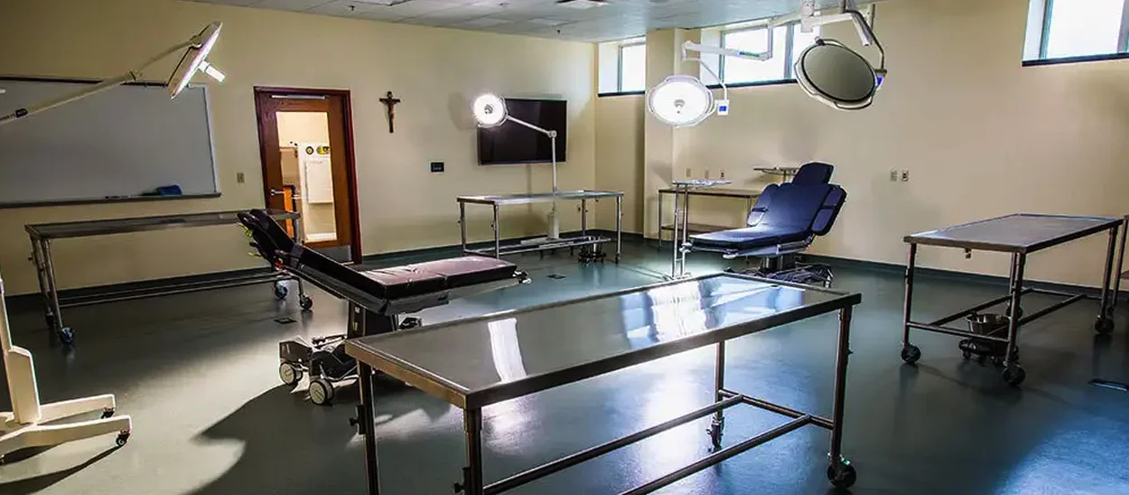 A sterile examination room featuring medical equipment including examination tables and overhead surgical lights.