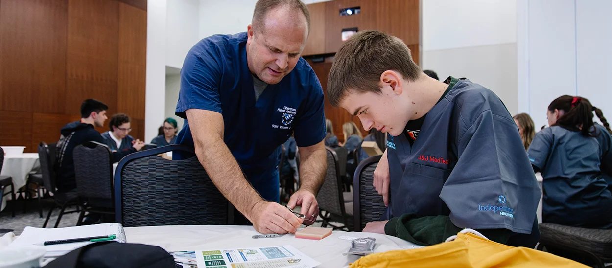 A medical professional demonstrates a procedure to a student during an educational workshop.