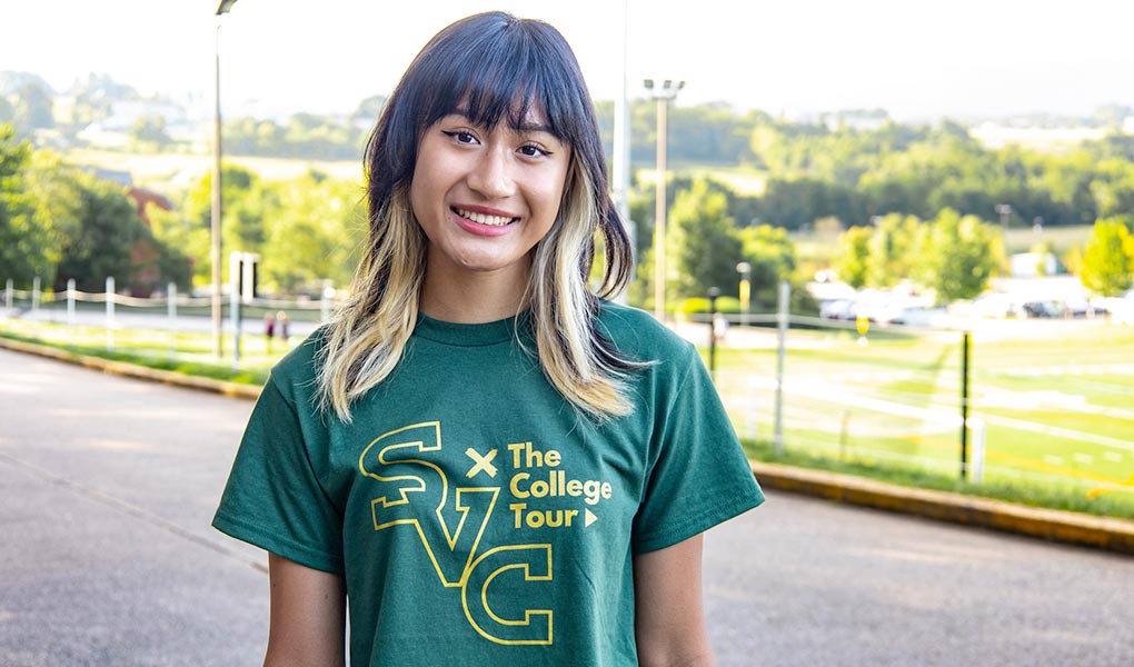 Student in SVC college tour t-shirt standing by the campus entrance