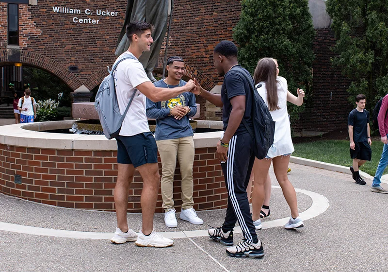 A group of college students socializing and interacting outside the William C. Ucker Center.