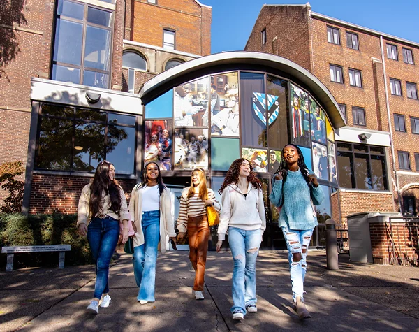 A group of five college age women walking together in front of a modern building with large windows, showcasing a collage of student life images.