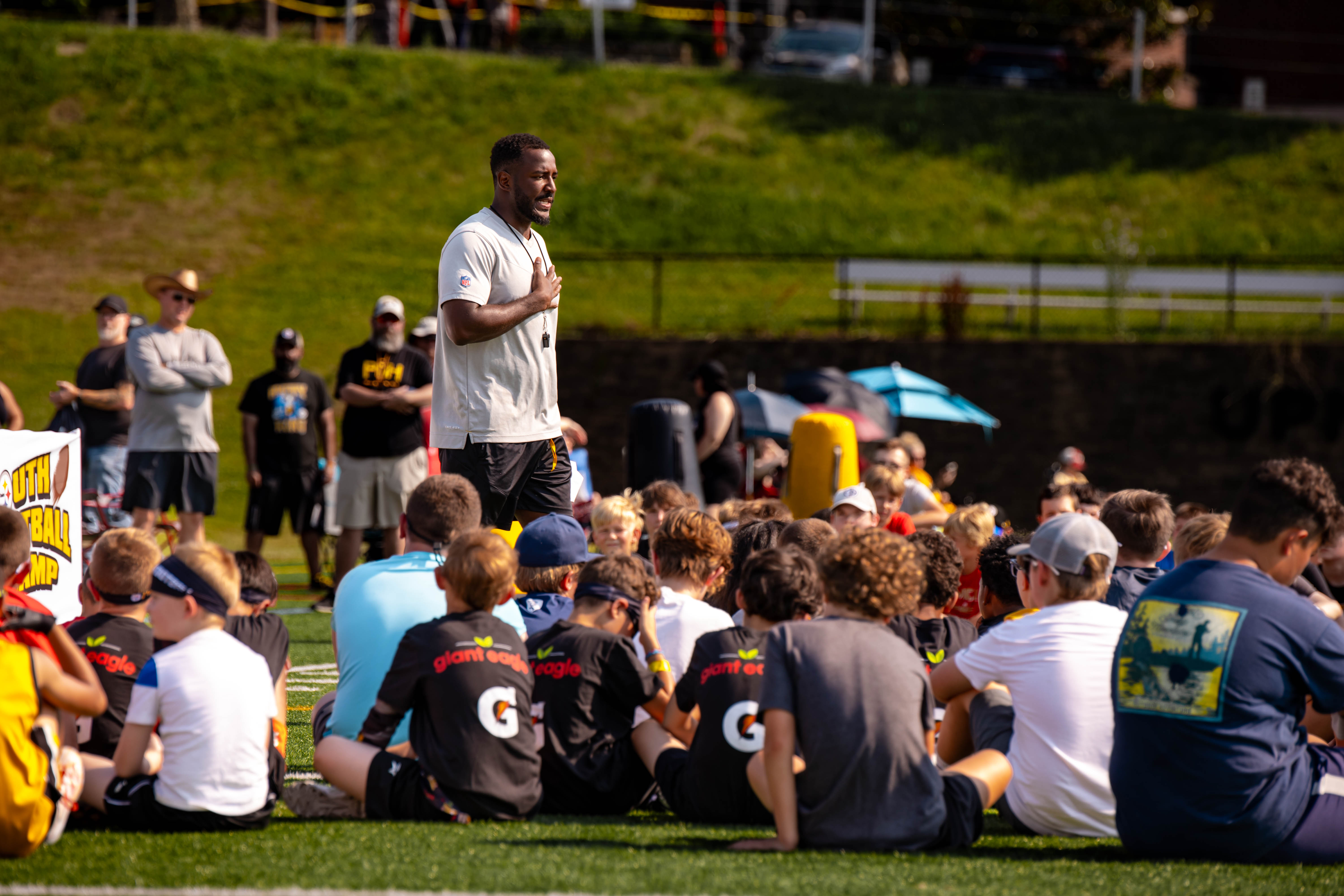 Camp director Joe Lofton (standing) talks to the campers during a break from drills