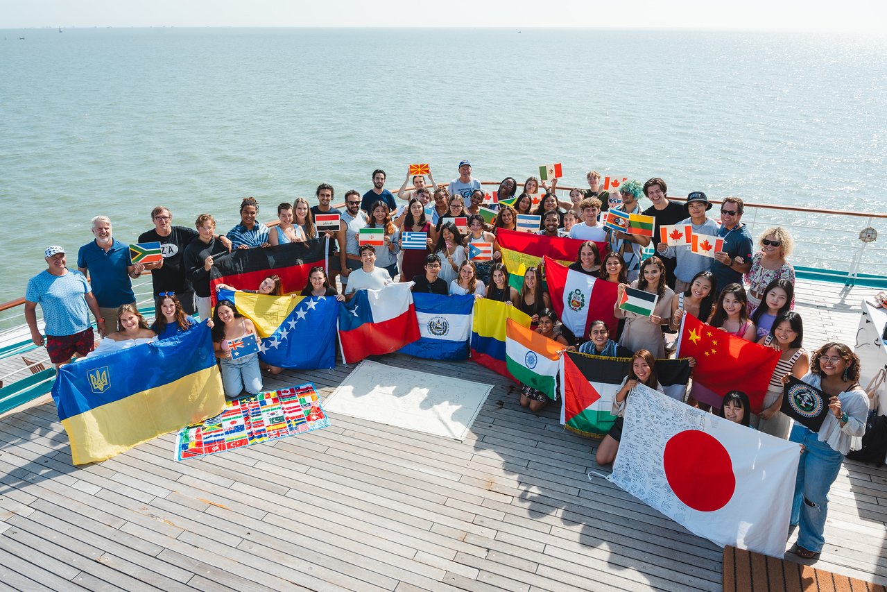 Students on the Fall 2023 Semester at Sea pose with flags of the countries represented on their voyage.