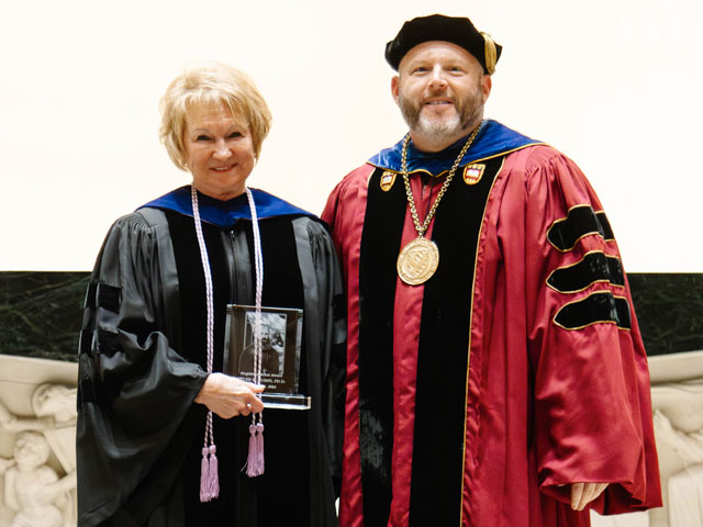 Dr. Helen Burns and Father Paul Taylor posing with the 2024 Projecktenmacher Award she received at the Saint Vincent Archabbey Basilica.