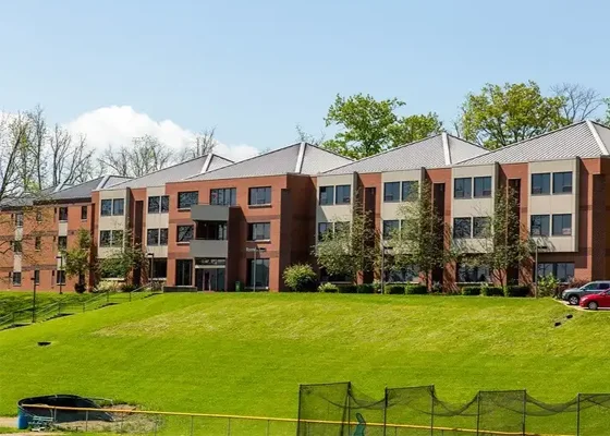 Rooney Hall, a modern residential building with multiple floors, surrounded by lush green grass and trees.