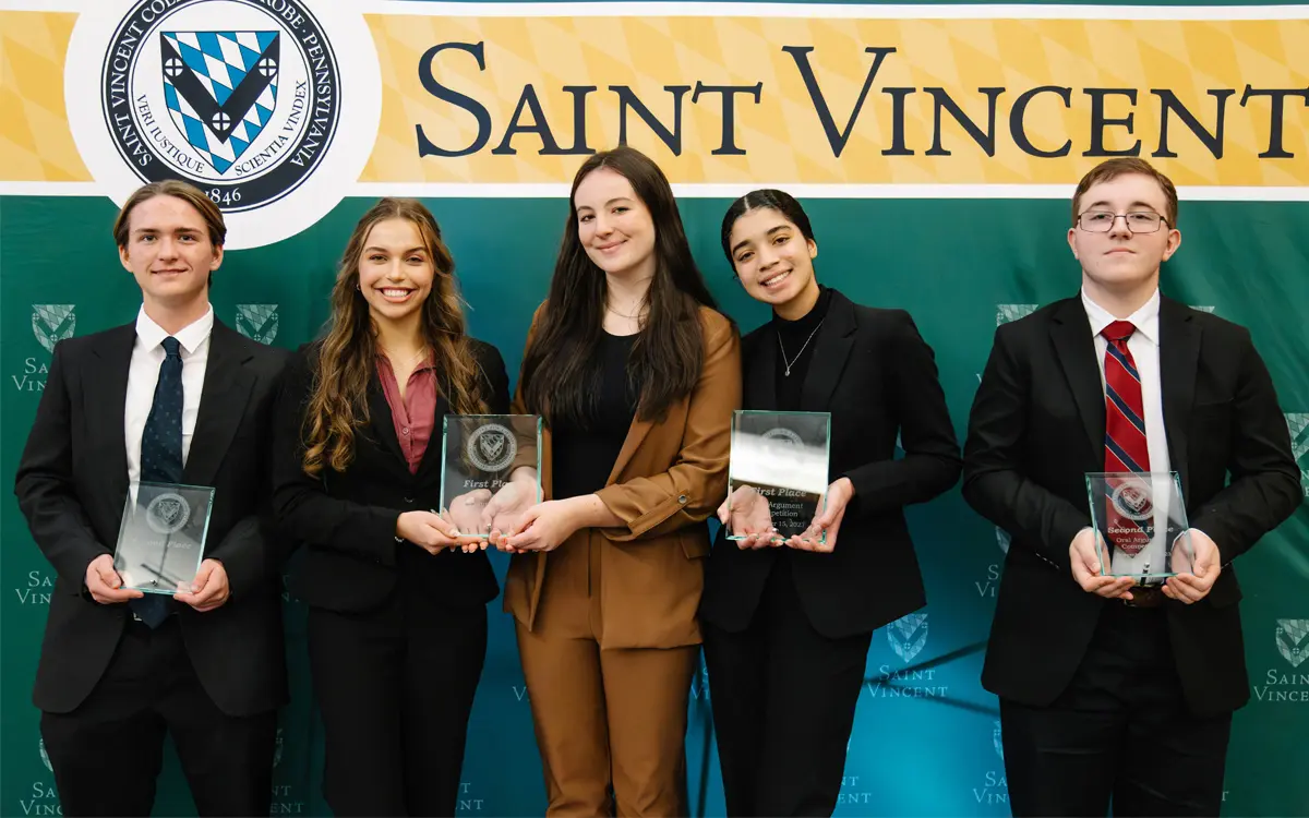 Five award recipients pose together, holding their trophies in front of a Saint Vincent backdrop.