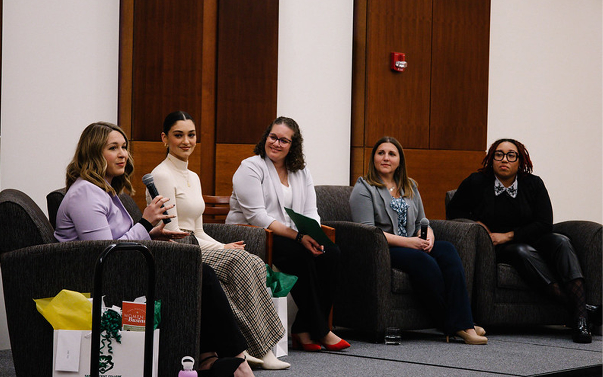 Panel discussion featuring five women seated on stage, engaging with the audience.