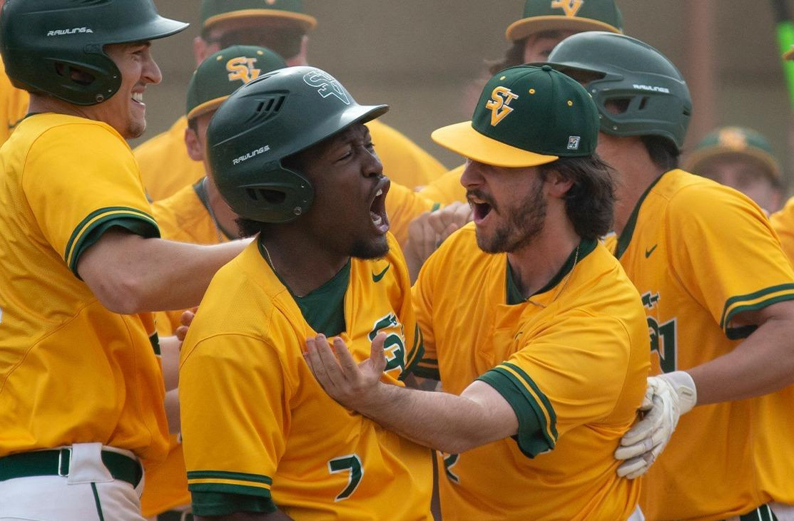 Team members celebrating a baseball victory, showcasing excitement and camaraderie in their bright yellow and green uniforms.