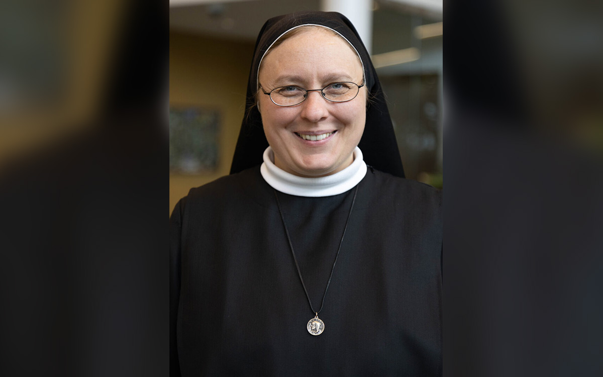 Sister Gabriele wearing a black habit and a silver medal necklace, with a warm and welcoming expression.