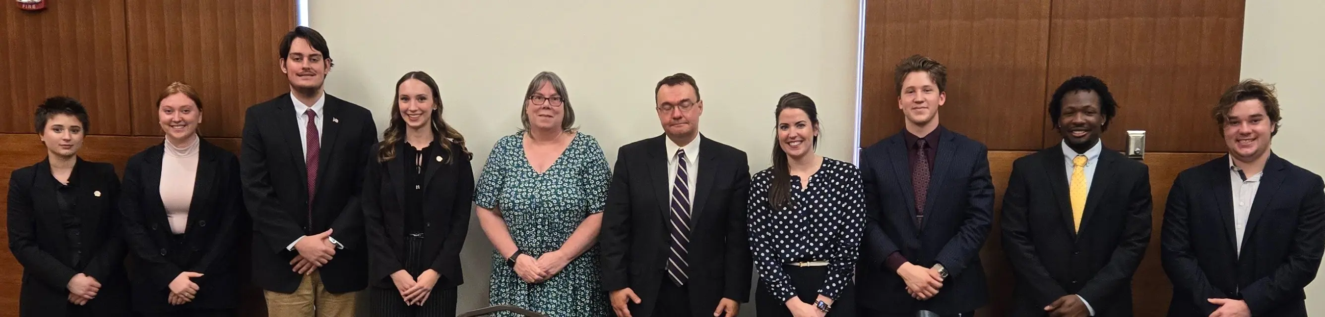 Group photo of a diverse team of professionals and students posing together in a formal setting.