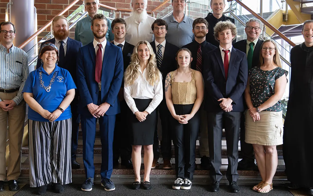 Group photo of a diverse group of students in formal attire, smiling in a lobby setting.