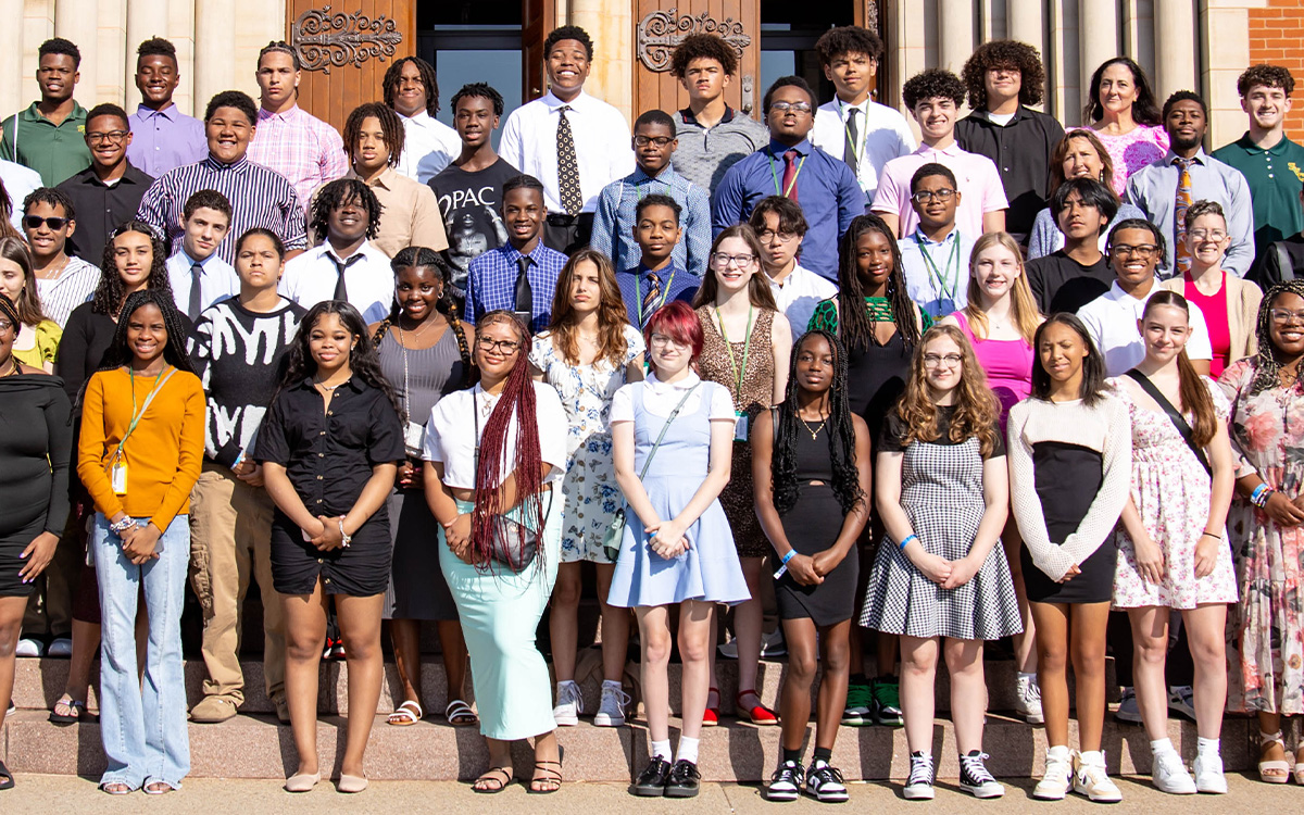 Group photo of diverse students gathered on a staircase outside the Basilica, smiling and posing together.