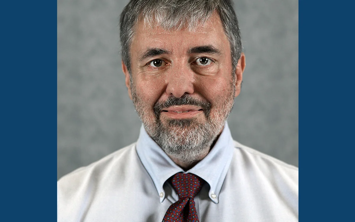 Portrait of Matt Fisher wearing a light blue dress shirt and a patterned tie.