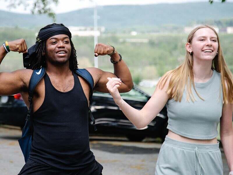 A joyful moment depicting a young man showing off his muscles while a young woman smiles and poses beside him.