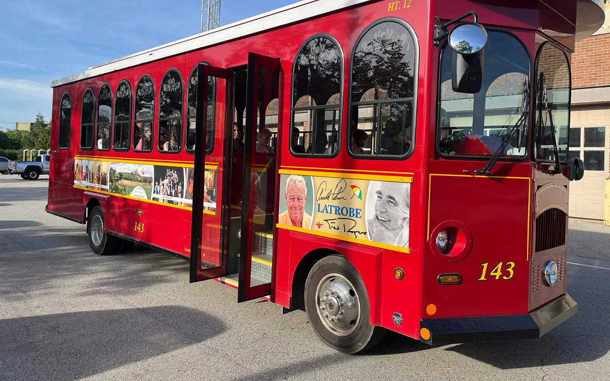 A red trolley bus with large windows and a vibrant exterior featuring promotional images and text.