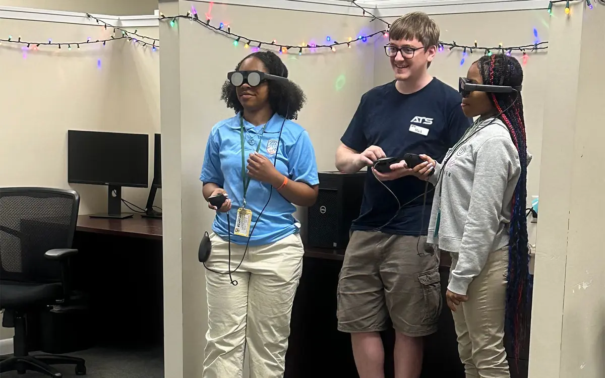 Students engage in a virtual reality experience with a facilitator in a decorated classroom.