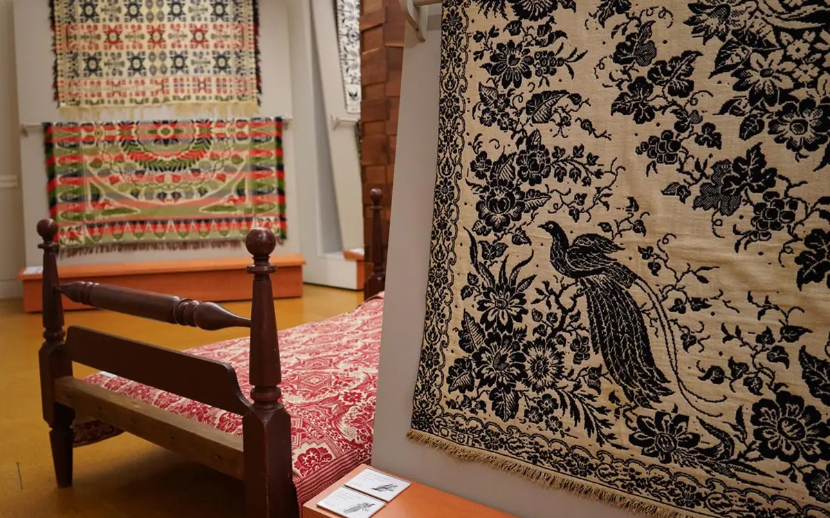 Exquisite woven textiles displayed in a gallery, showcasing intricate designs and rich colors.