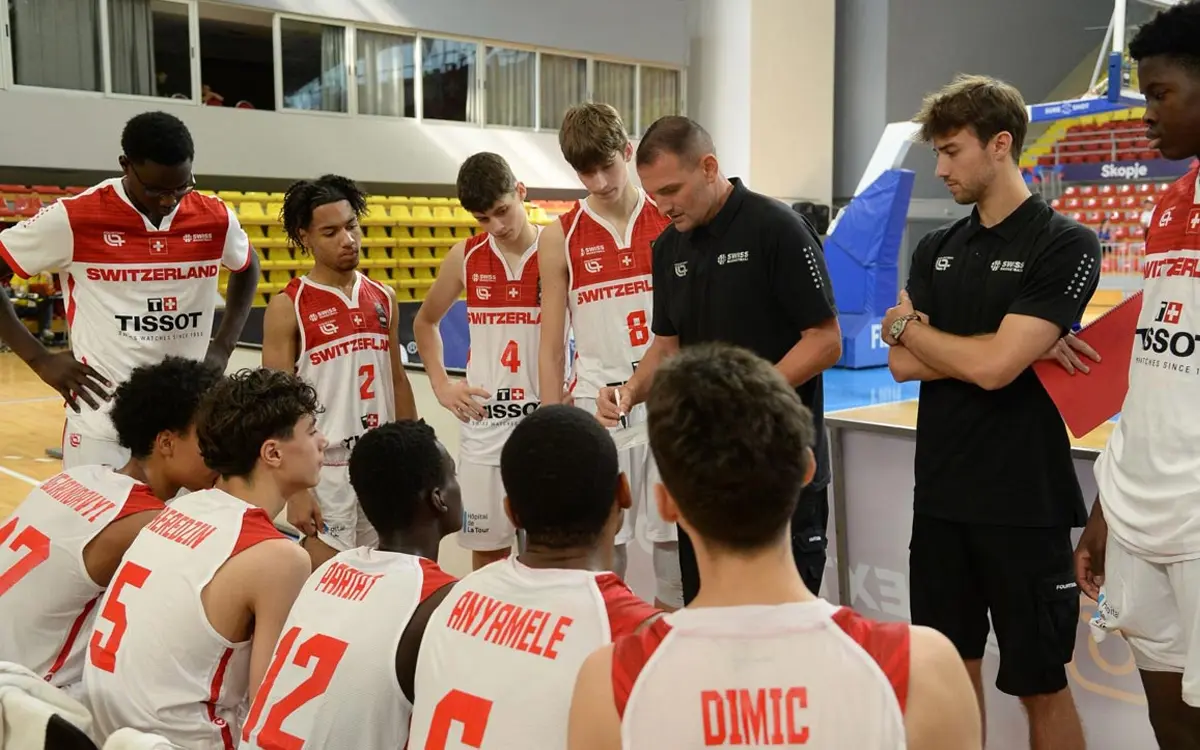 Julian Vonovier (second from right) listens as Switzerland’s head coach, Mitar Trivunovic (center), instructs the team during a timeout