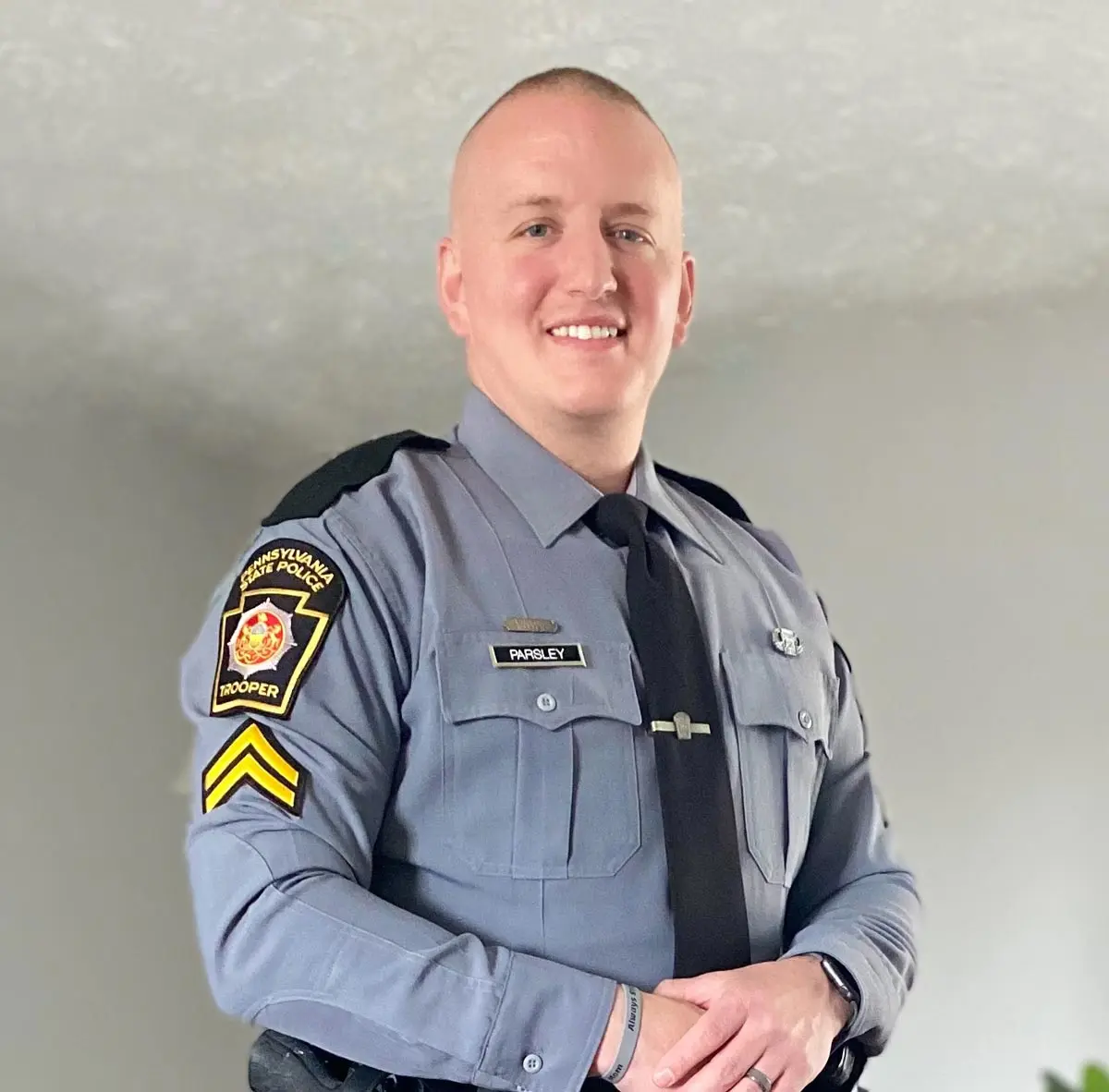 Portrait of a smiling police officer in uniform, showcasing his badge and rank insignia.