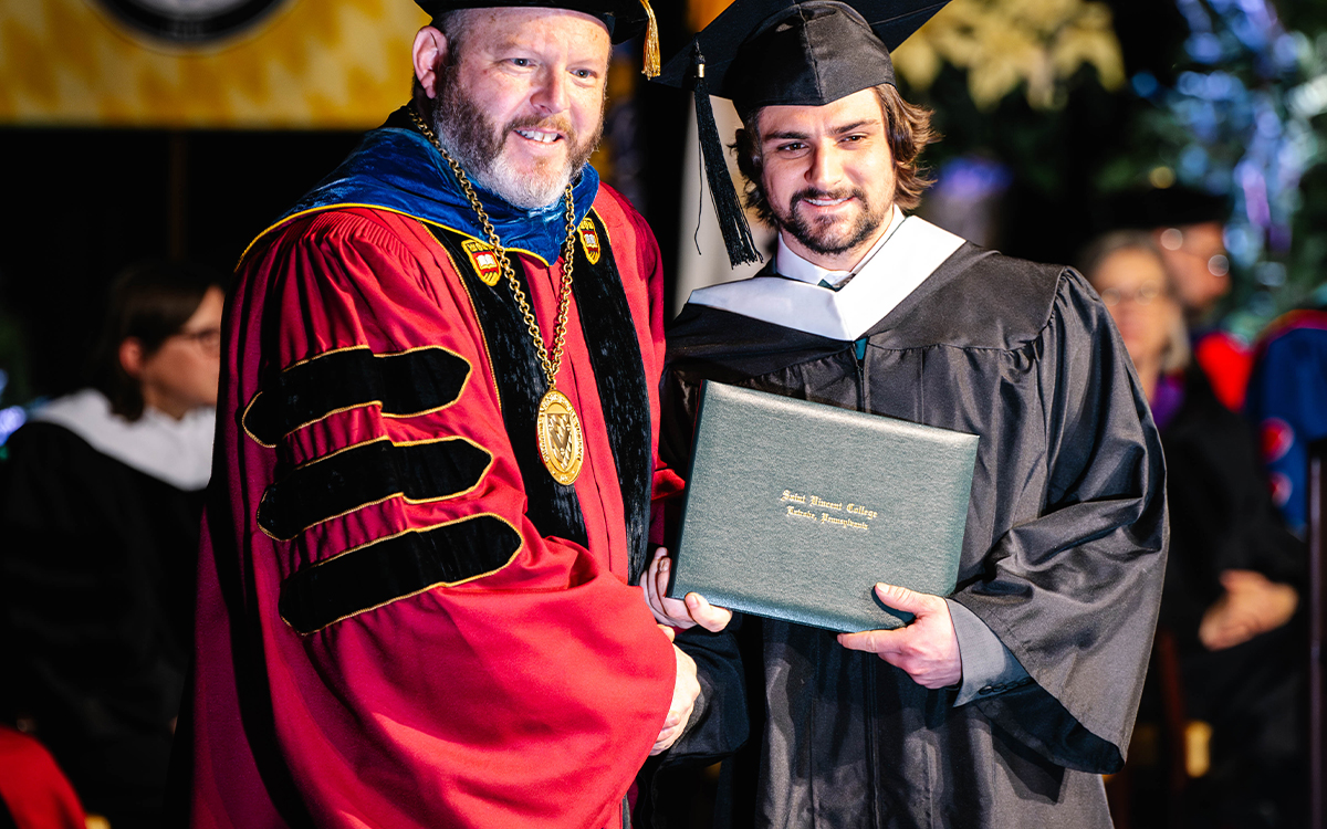 A graduate receiving their diploma from a university official during a commencement ceremony.